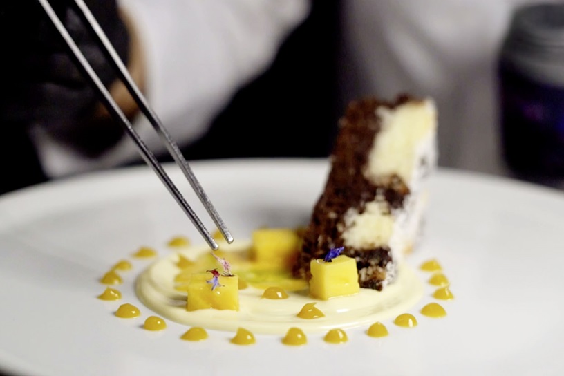 Porciones de Tarta de Chocolate Y Coco con salsa de vainilla y puré de mango